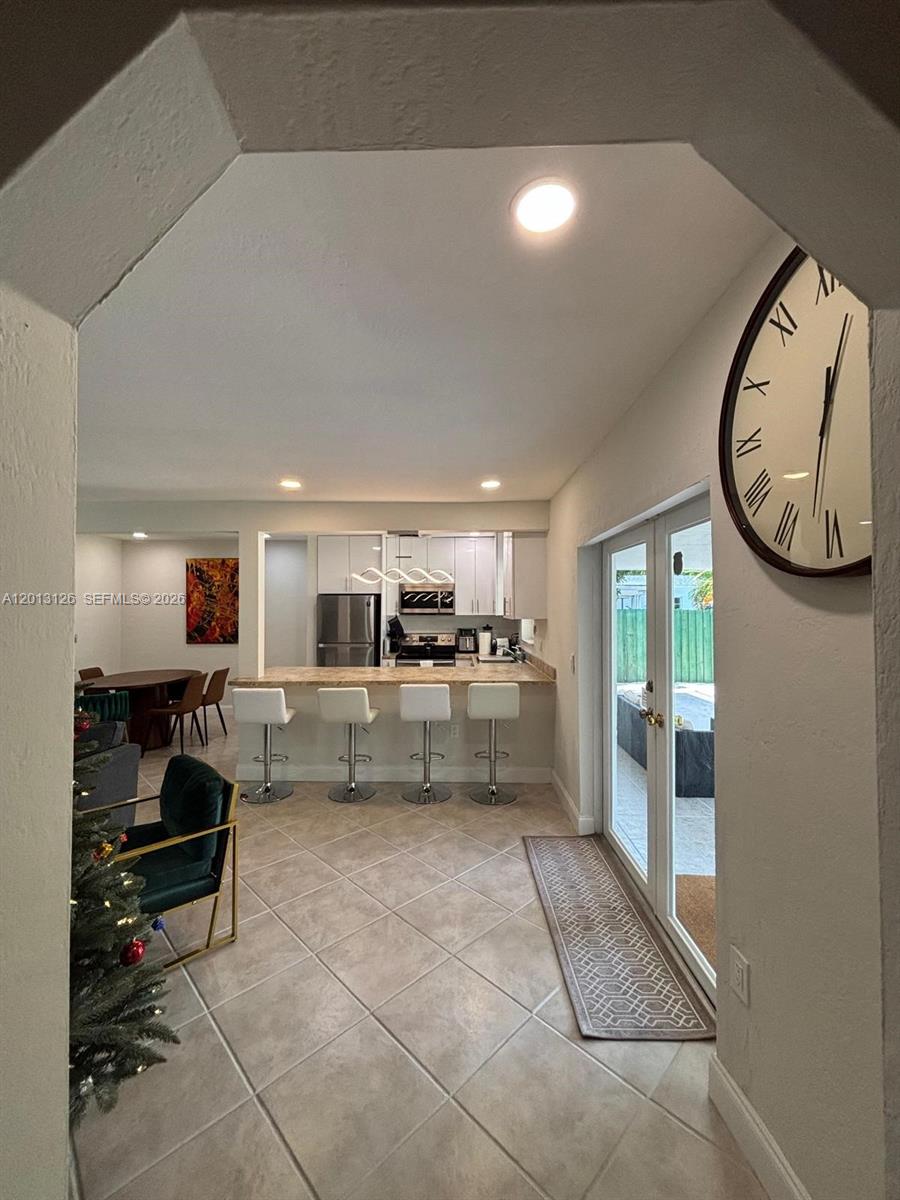A kitchen with white cabinets and a breakfast bar overlooks a dining area and patio — 1931 Mayo St, Hollywood FL 33020, HOLLYWOOD, FL