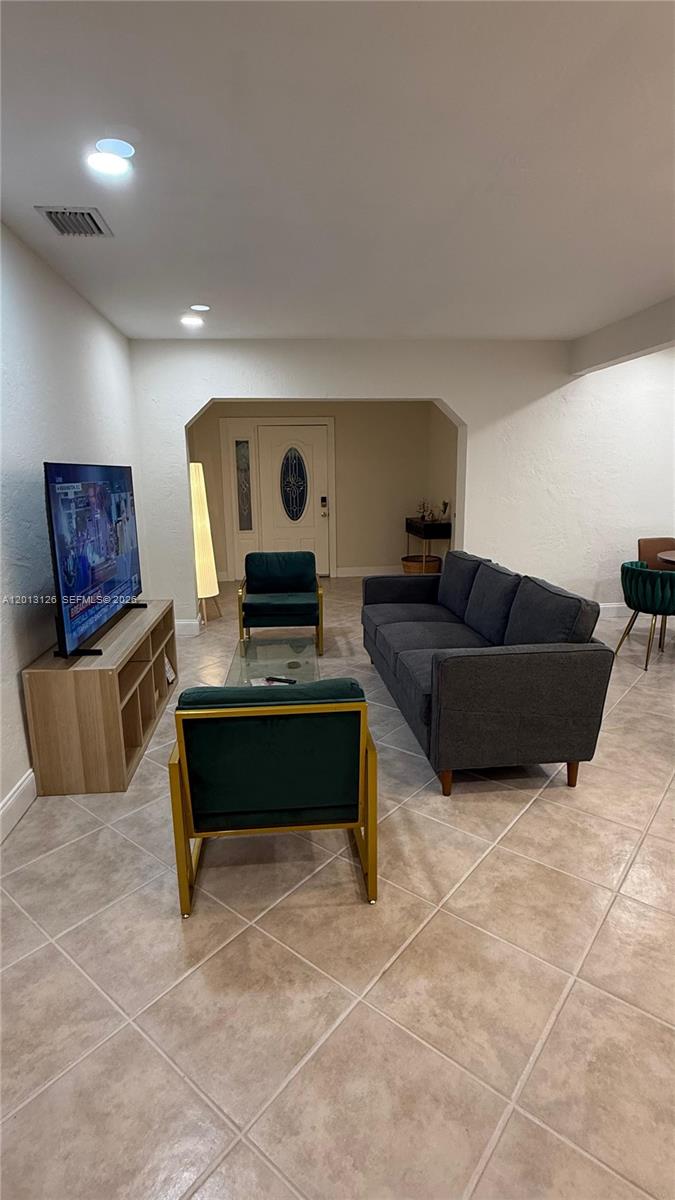 A living room features a gray sofa, two green armchairs, and a television on a stand — 1931 Mayo St, Hollywood FL 33020, HOLLYWOOD, FL