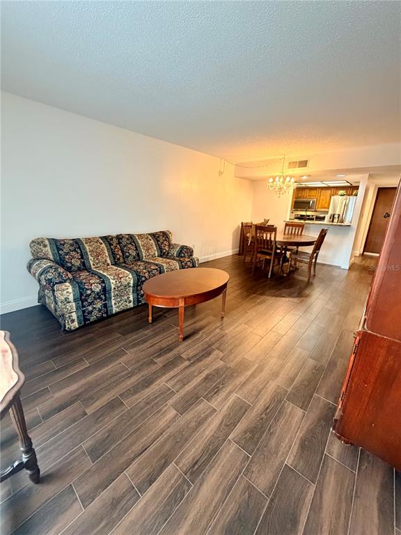 A living room with a floral sofa, wood coffee table, and dining area with wood floors — 13602 S VILLAGE DRIVE UNIT 1106, TAMPA, FL