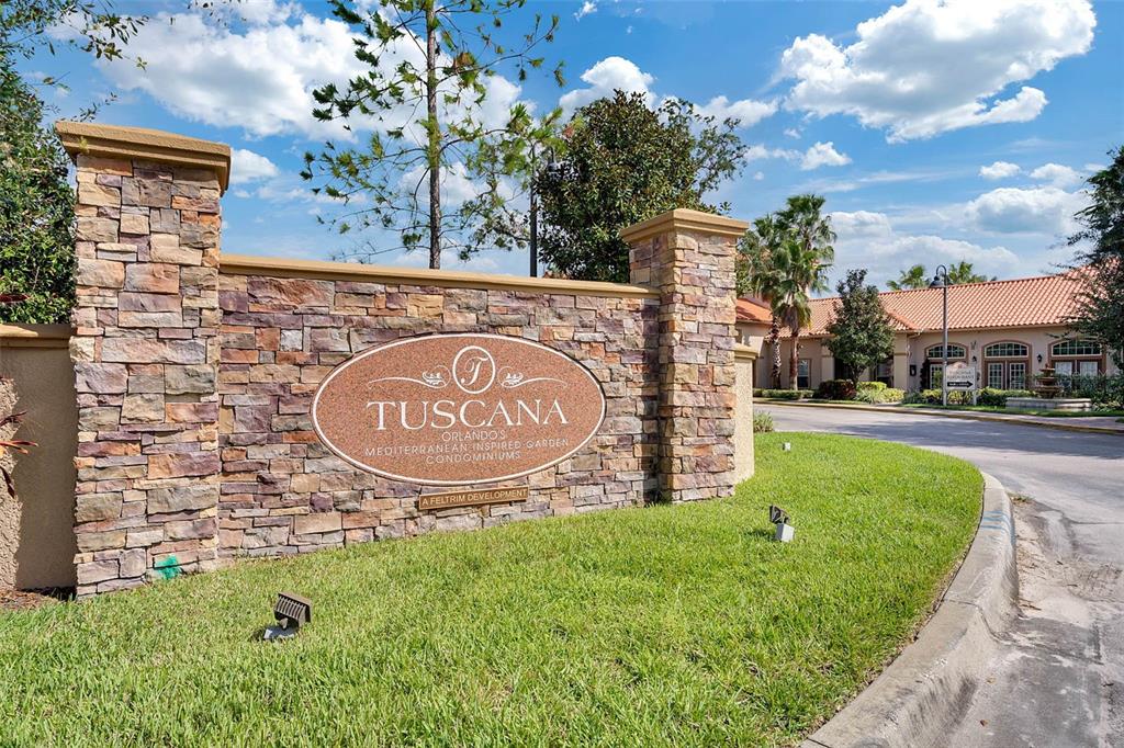 A stone monument sign for Tuscana condominiums stands in a grassy area near a road — 1375 TUSCANA LANE UNIT 1108, DAVENPORT, FL