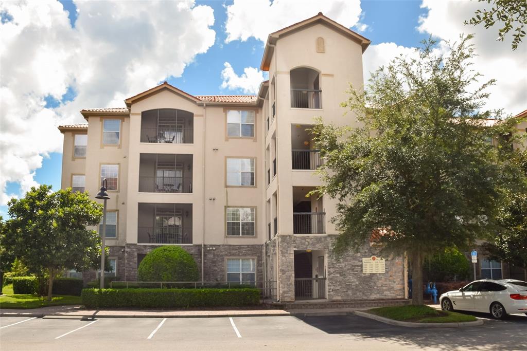 A multi-story apartment building features stucco walls, stone veneer accents, and screened balconies — 1375 TUSCANA LANE UNIT 1108, DAVENPORT, FL