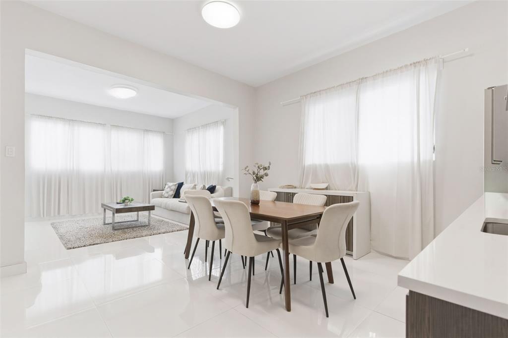A bright dining area with a wooden table and chairs opens into a living room — 56 CALLE F KRUG CONDADO UNIT 2, SAN JUAN, PR
