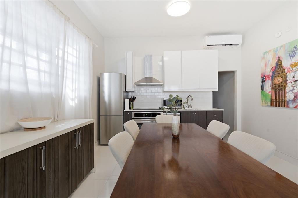 A modern kitchen and dining area features a wooden table, white chairs, and stainless appliances — 56 CALLE F KRUG CONDADO UNIT 2, SAN JUAN, PR