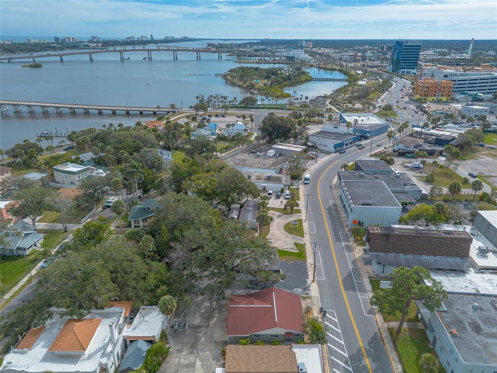 Aerial view of a coastal town featuring a bridge, water, and nearby commercial and residential buildings — 555 BALLOUGH ROAD, DAYTONA BEACH, FL