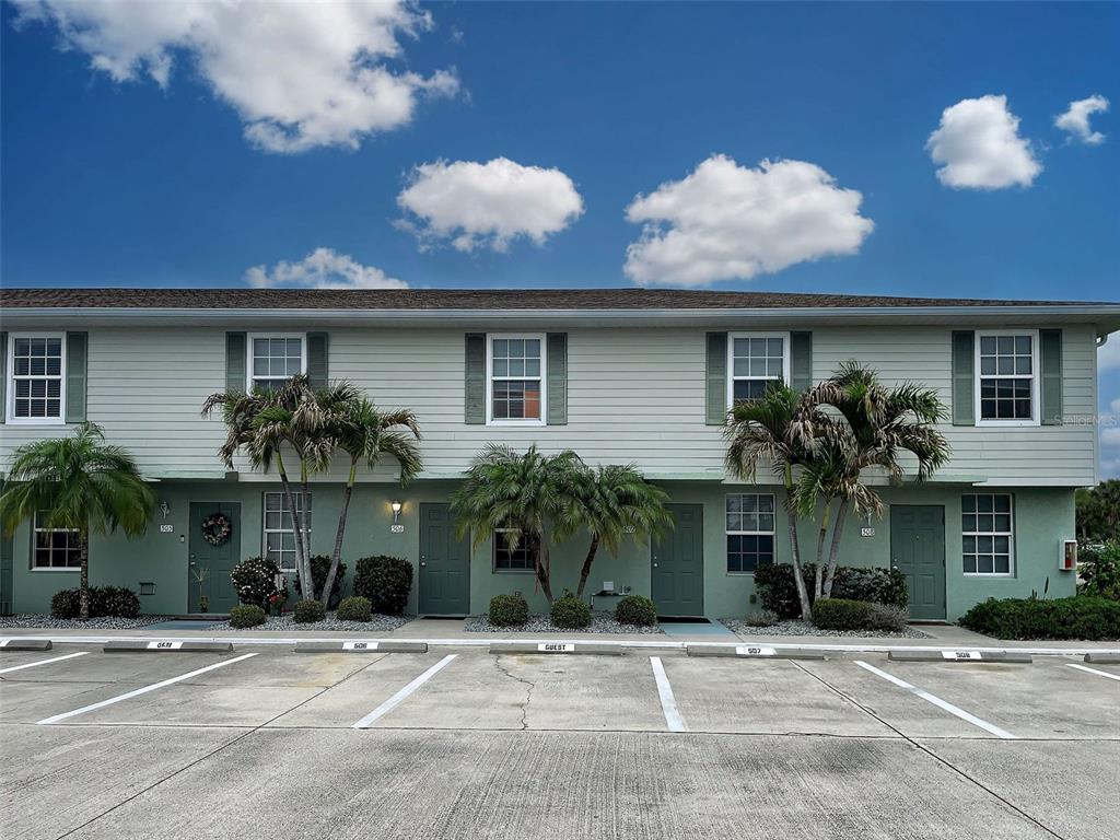 A two-story apartment building with light green siding and assigned parking spaces in front — 26396 NADIR ROAD UNIT 506, PUNTA GORDA, FL