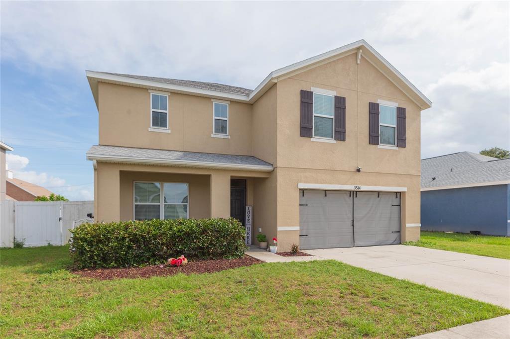 A two-story tan stucco house features a two-car garage and a front porch — 3514 SAN MOISE PLACE, PLANT CITY, FL