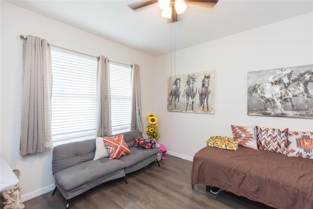 A room with wood-look flooring, a gray futon, a bed, and horse-themed wall art — 3514 SAN MOISE PLACE, PLANT CITY, FL