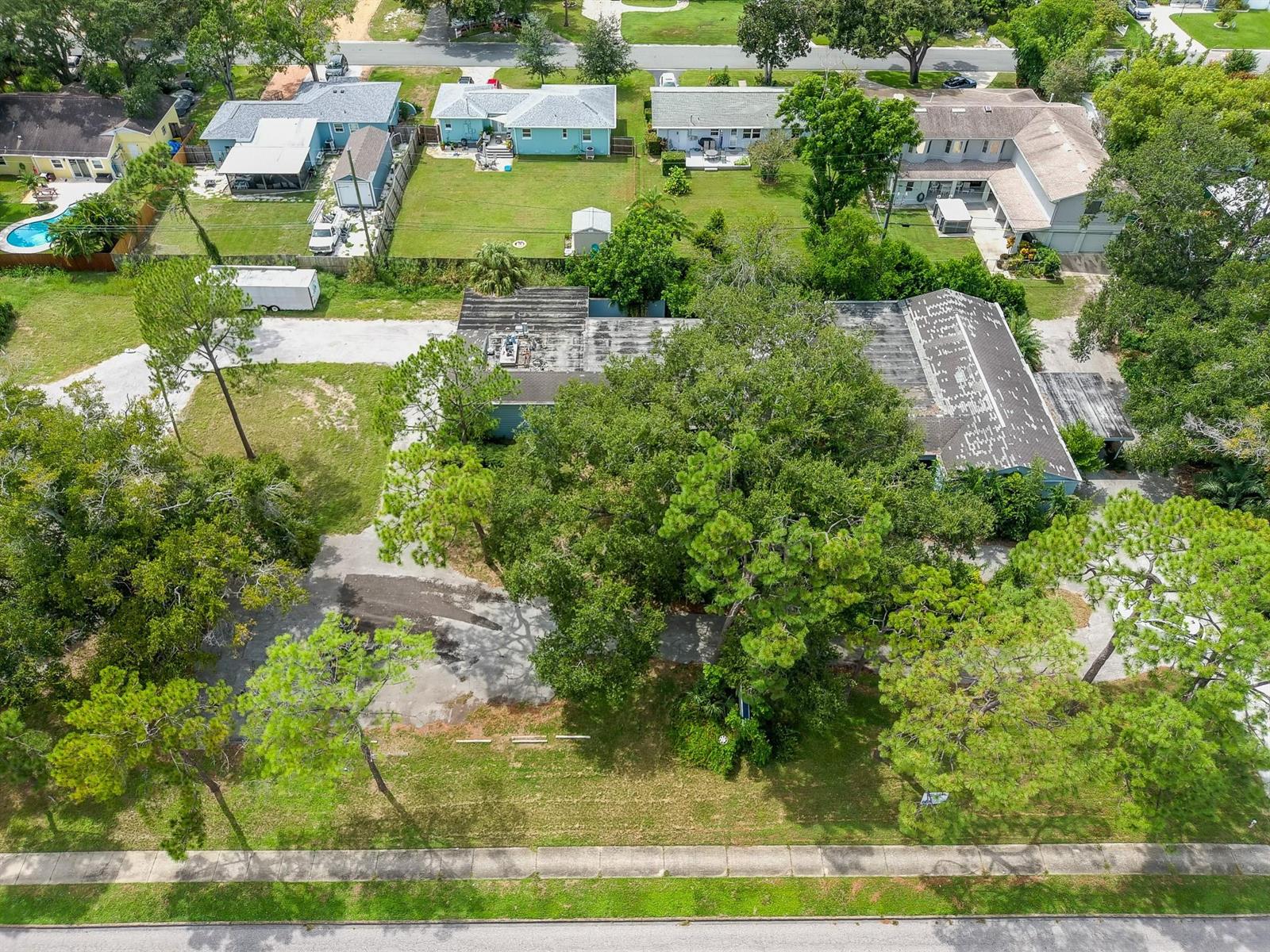 An aerial view shows a large, flat-roofed building surrounded by trees and a paved lot — 4100 N 16th Street, FL 33703, FL