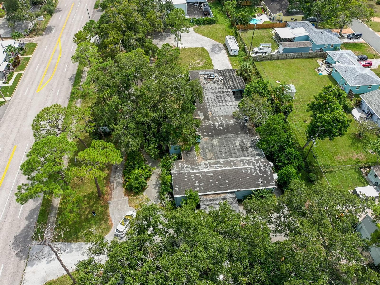 An aerial view shows a flat-roofed commercial building surrounded by trees and a paved driveway — 4100 N 16th Street, FL 33703, FL