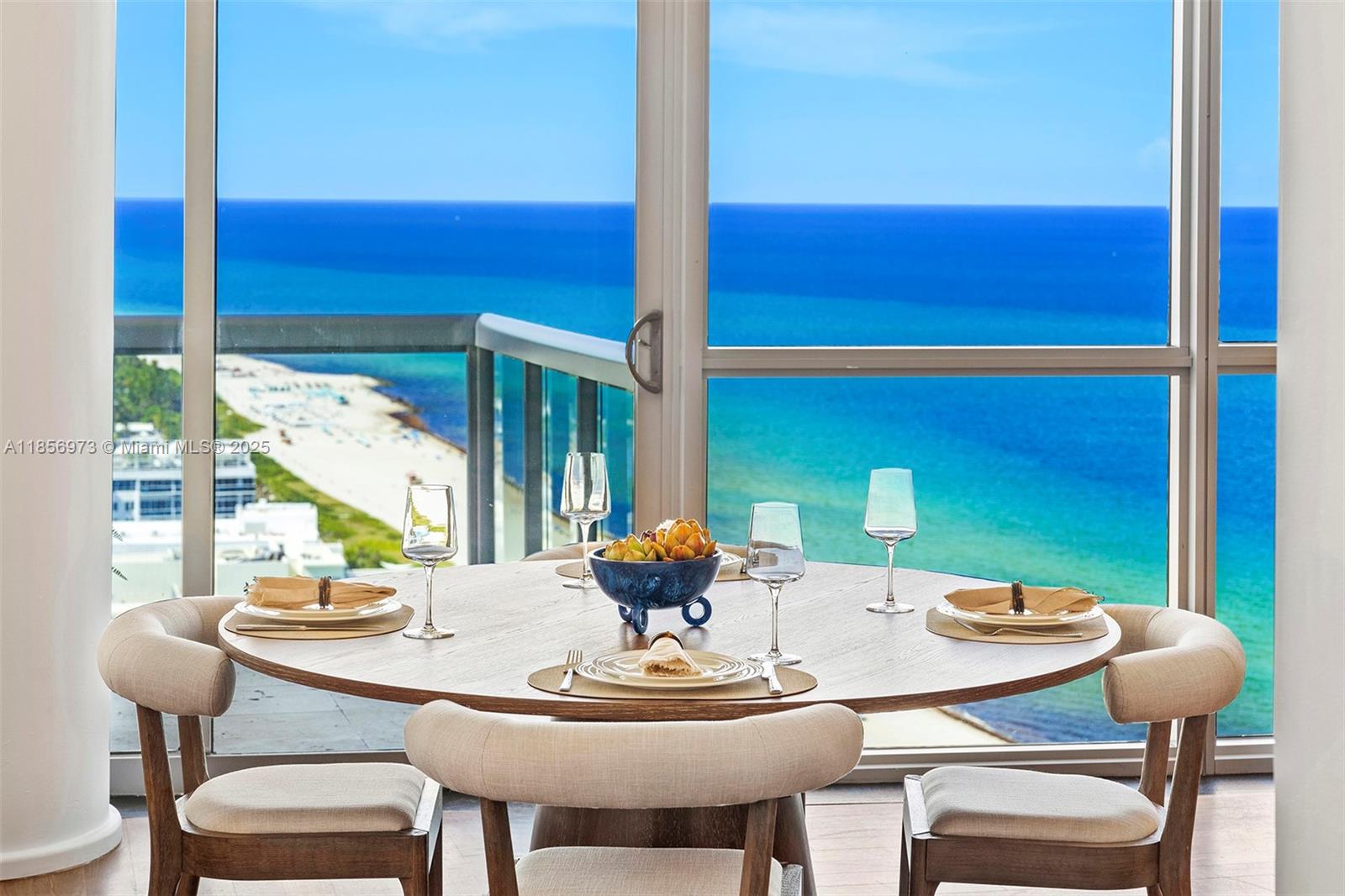 A round dining table with four chairs sits before floor-to-ceiling windows overlooking the ocean — 101 20th St # 3803, Miami Beach FL 33139, MIAMI BEACH, FL
