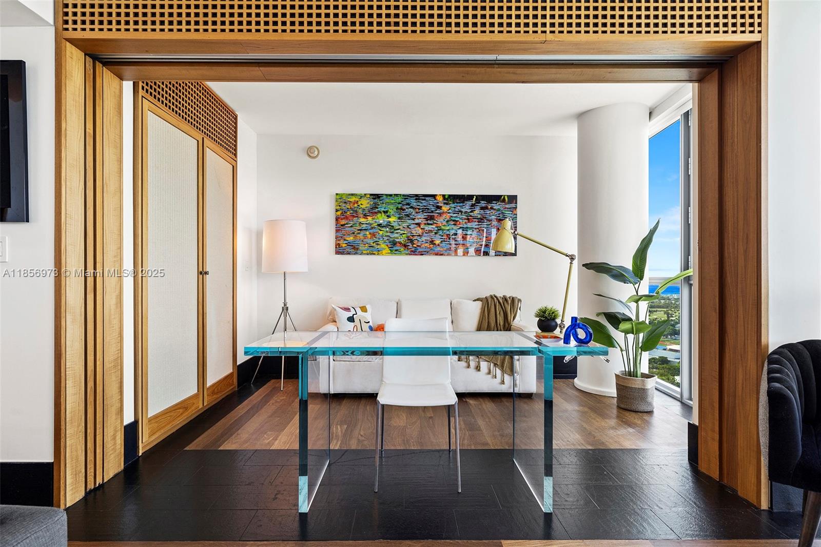 A glass desk sits in a room with wood flooring, a sofa, and a large window — 101 20th St # 3803, Miami Beach FL 33139, MIAMI BEACH, FL
