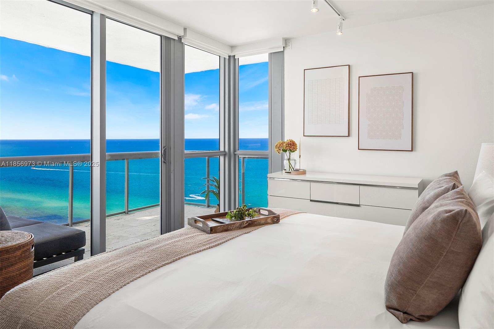 A bedroom features a white bed, a dresser, and floor-to-ceiling windows overlooking the ocean — 101 20th St # 3803, Miami Beach FL 33139, MIAMI BEACH, FL