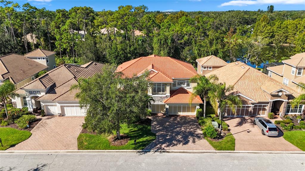 An aerial view shows three suburban houses with tile roofs and paved driveways — 8134 SANTA ROSA COURT, SARASOTA, FL