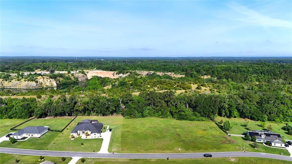 An aerial view shows two houses on a street bordering a large, wooded, undeveloped lot — XX NW 79TH LOOP, OCALA, FL