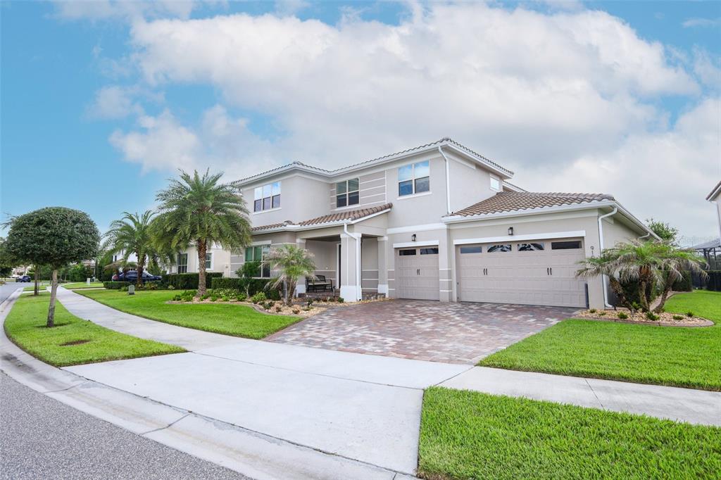 A two-story suburban house with a paver driveway, three-car garage, and manicured lawn — 9103 MORGANA COURT, WINTER GARDEN, FL