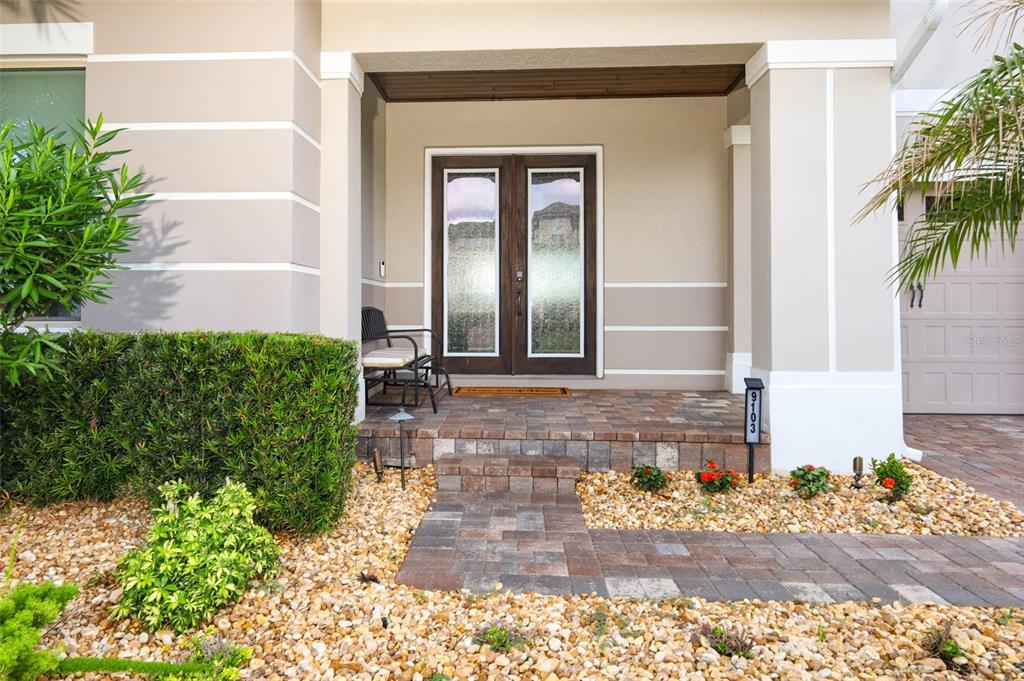 A paved walkway leads to the covered front porch and double glass doors of a house — 9103 MORGANA COURT, WINTER GARDEN, FL