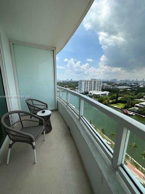 A balcony with two chairs and a small table overlooks a waterway and city skyline — 4401 Collins Ave # 1817, Miami Beach FL 33140, MIAMI BEACH, FL