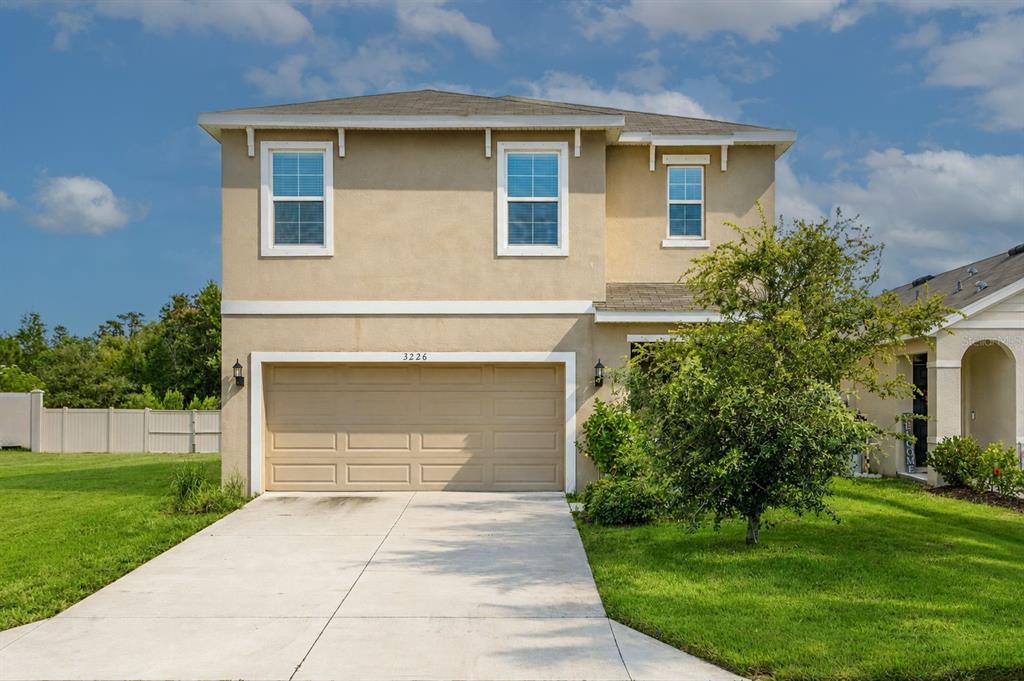 A two-story tan house with a two-car garage and a concrete driveway — 3226 SUNCOAST PLAINS DRIVE, ODESSA, FL