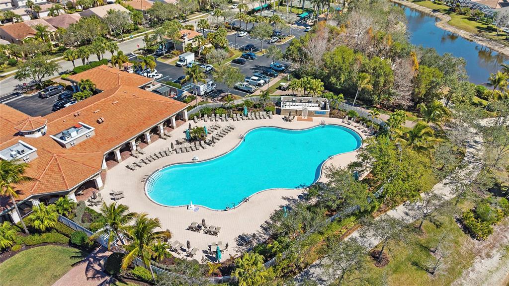 An aerial view shows a community swimming pool with a surrounding patio and clubhouse — 15127 REEF LANE, BONITA SPRINGS, FL