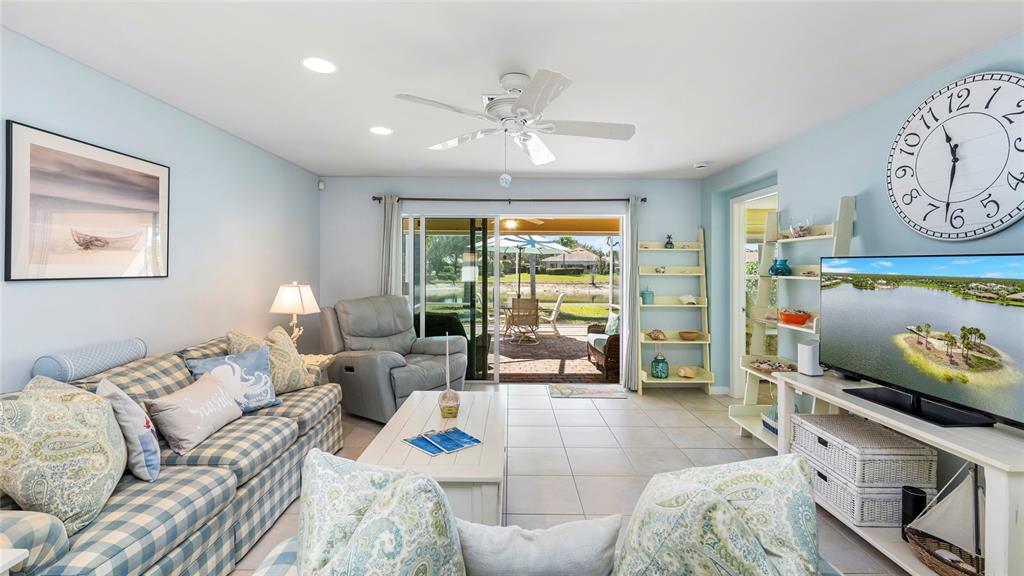 A living room features a plaid sofa, a recliner, a television, and sliding glass doors — 15127 REEF LANE, BONITA SPRINGS, FL