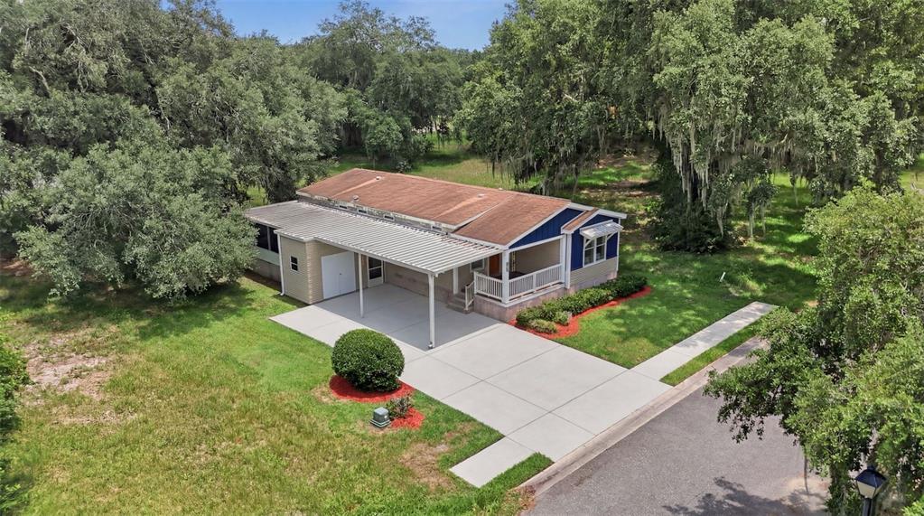 An aerial view shows a single-story house with a metal carport and a front porch — 25138 BUTTONWOOD DRIVE, ASTATULA, FL