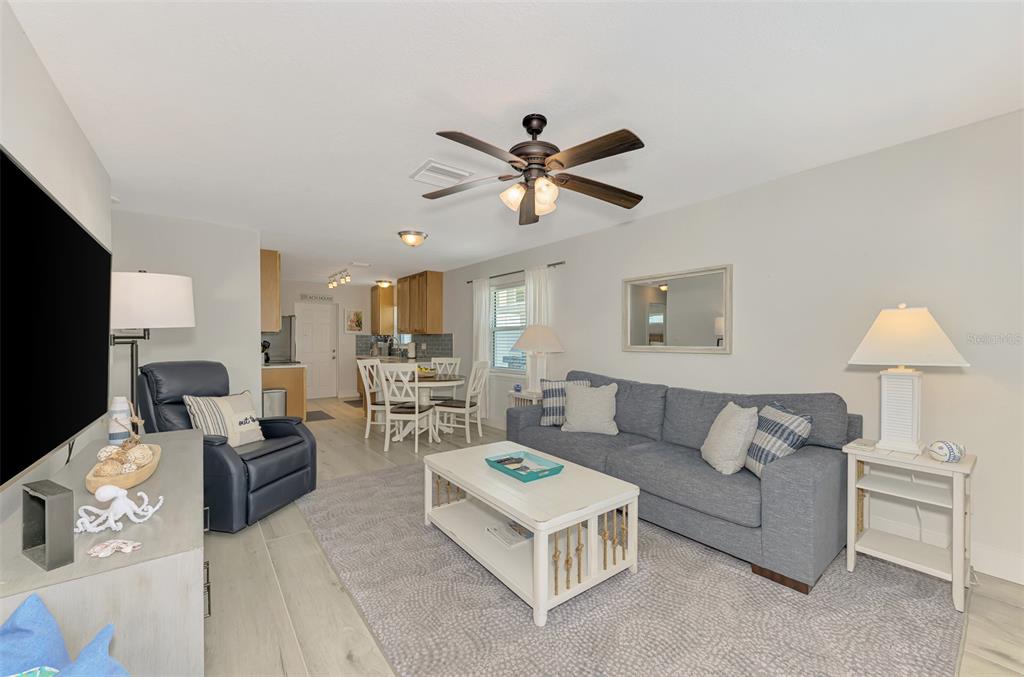 A living room with a gray sofa, blue recliner, coffee table, and adjacent dining area — 1137 N MOONMIST COURT UNIT L-7, SARASOTA, FL