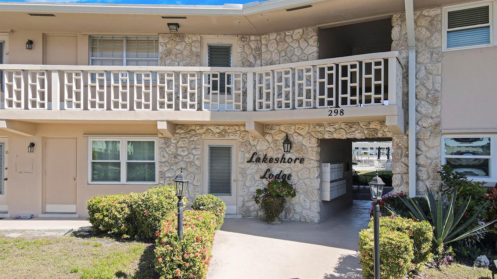 The exterior of a two-story building features stone masonry, a balcony, and a walkway entrance — 298 SE 6th Avenue # 6, Pompano Beach FL 33060, POMPANO BEACH, FL