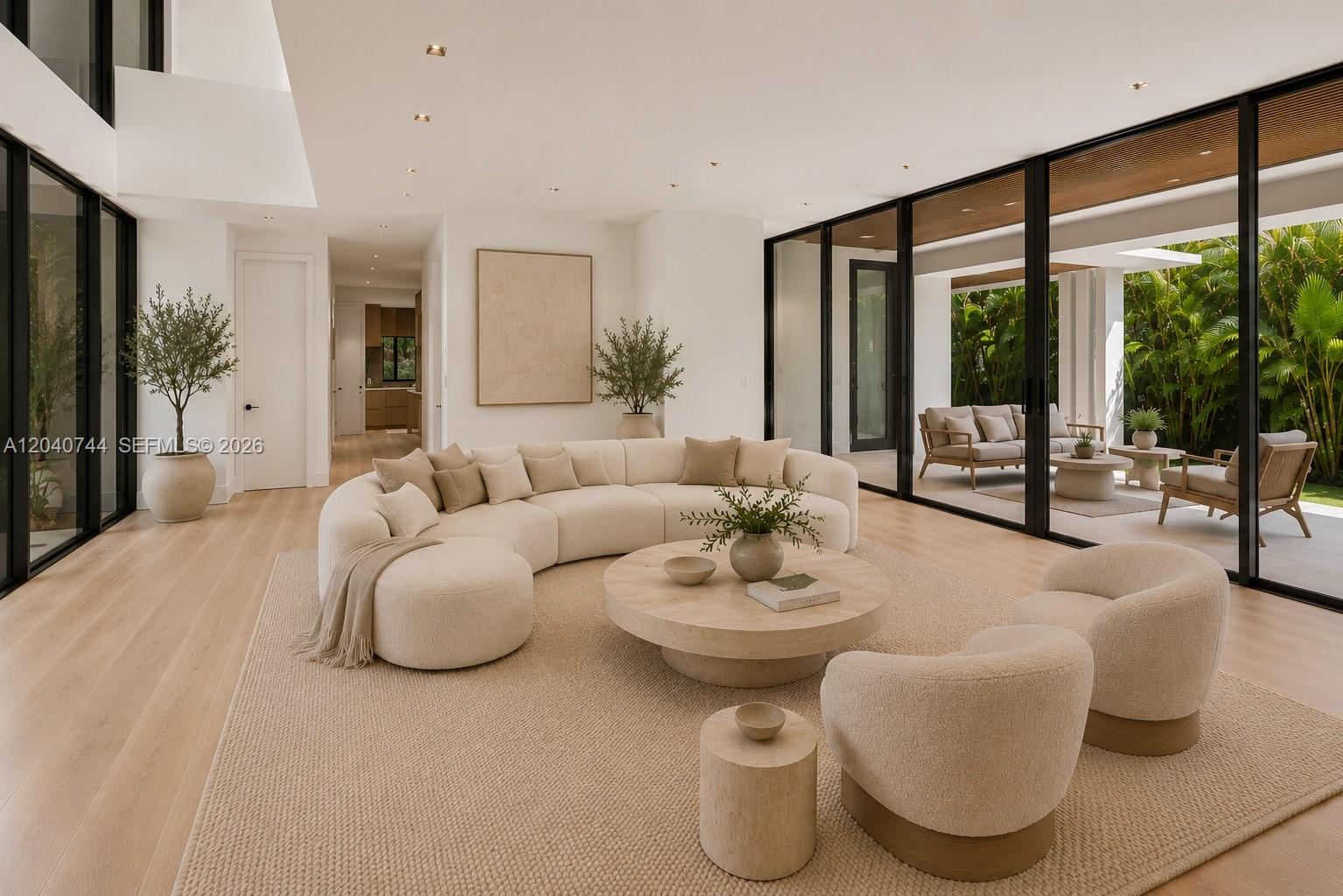 A modern living room features a curved sofa, circular coffee table, and floor-to-ceiling glass walls — 165 Hampton Ln, Key Biscayne FL 33149, KEY BISCAYNE, FL