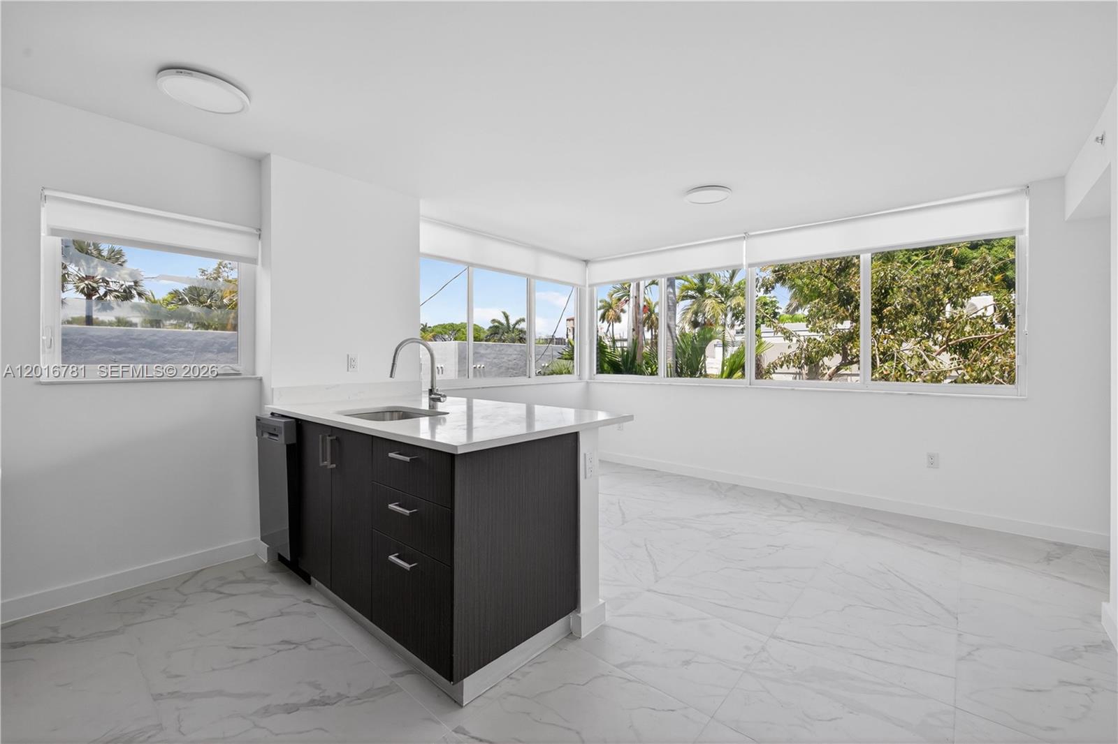 A kitchen island with dark cabinets and a white countertop sits in a bright room — 1552 Euclid Ave # 08, Miami Beach FL 33139, MIAMI BEACH, FL