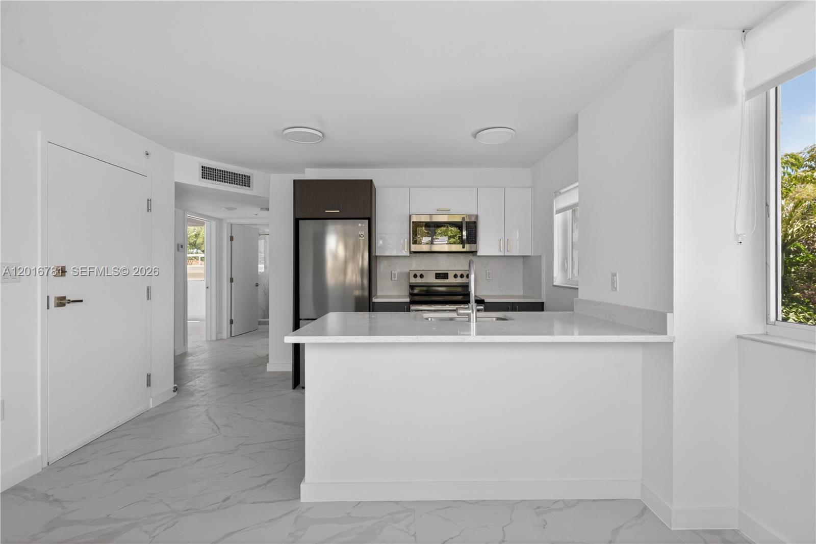 A modern kitchen features white cabinets, stainless steel appliances, and a white quartz island — 1552 Euclid Ave # 08, Miami Beach FL 33139, MIAMI BEACH, FL