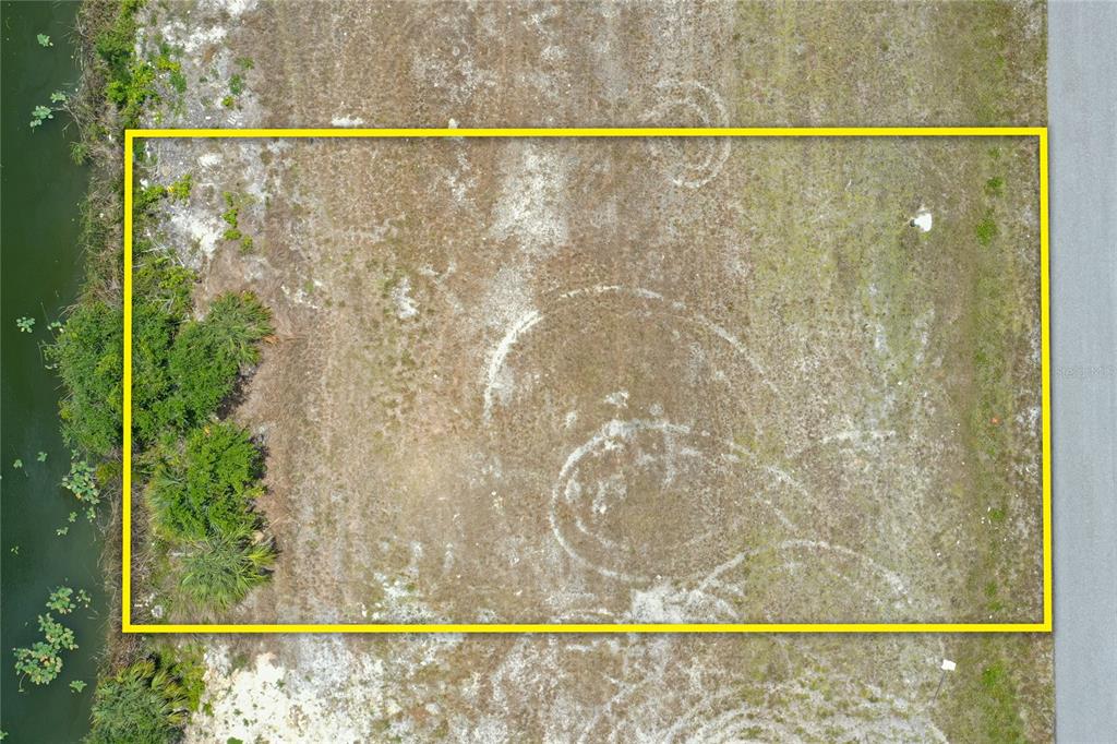 An aerial view shows a rectangular vacant lot bordered by a body of water — 3023 NE 5TH PLACE, CAPE CORAL, FL