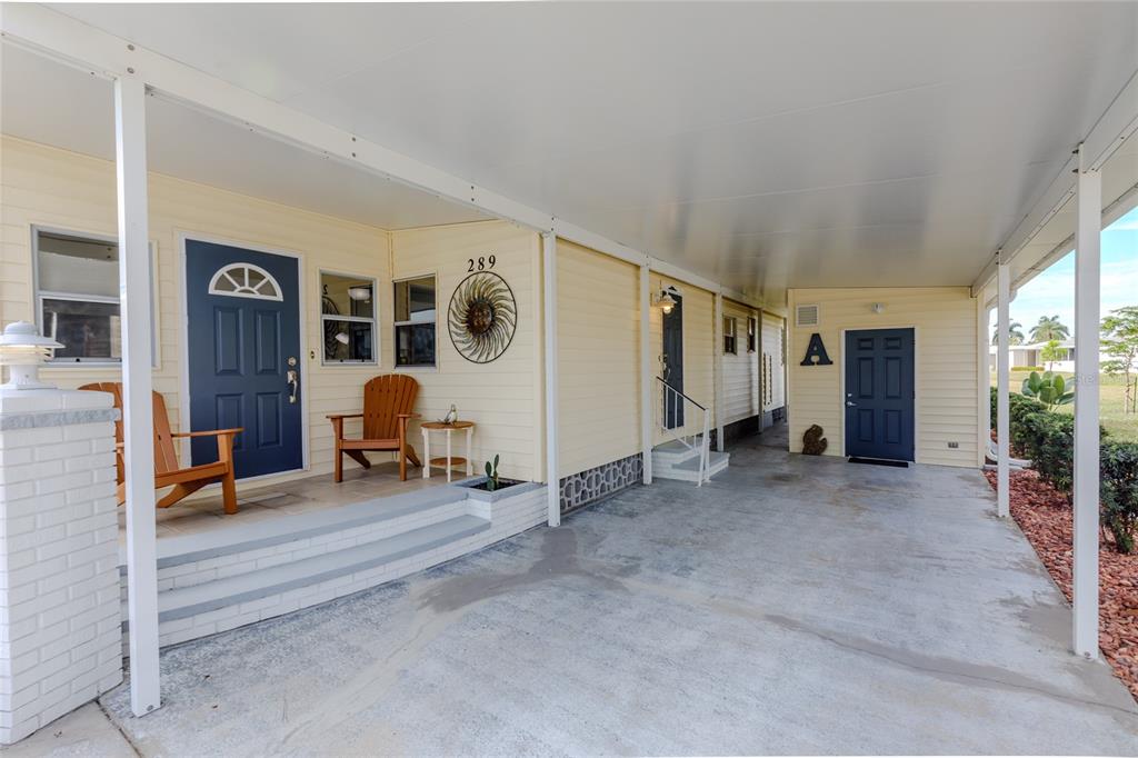 A light yellow mobile home features a covered carport, a front porch, and blue doors — 2100 KINGS HIGHWAY UNIT 289, PORT CHARLOTTE, FL