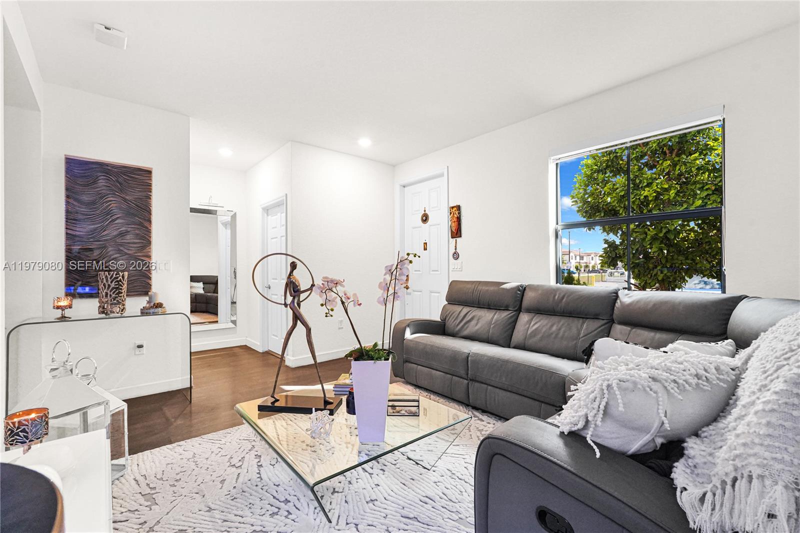 A living room features a gray leather sofa, a glass coffee table, and white walls — 3321 W 105th Pl, Hialeah FL 33018, HIALEAH, FL