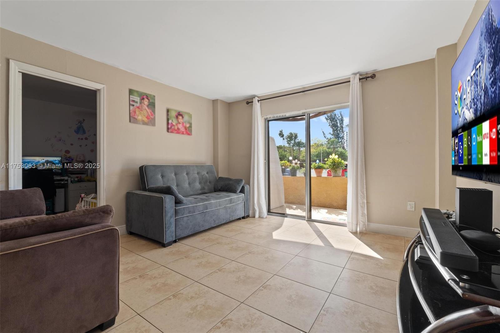 A living room features tile flooring, a gray sofa, a television, and a sliding glass door — 4801 NW 7th St # 16, Miami FL 33126, MIAMI, FL