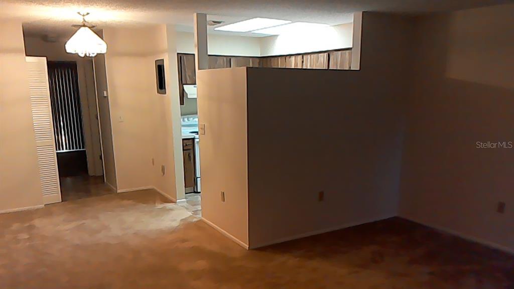 An interior view shows a carpeted living area with a partial wall separating the kitchen — 706 GREEN VALLEY ROAD UNIT E4, PALM HARBOR, FL