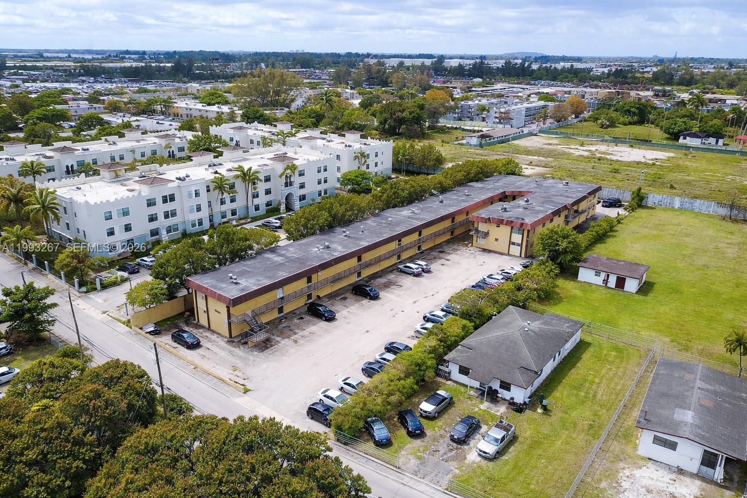 An aerial view shows a long, yellow multi-story apartment building with a parking lot — 13380 Port Said Rd, Opa-Locka FL 33054, OPA-LOCKA, FL