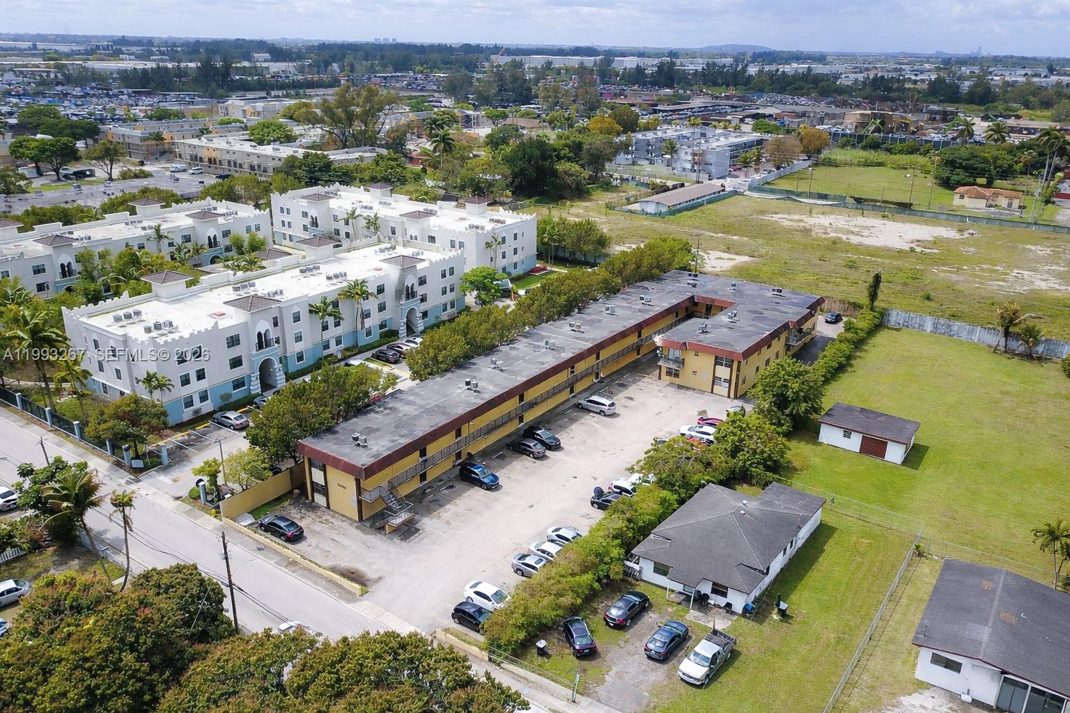 An aerial view shows a two-story apartment building with a parking lot and surrounding greenery — 13380 Port Said Rd, Opa-Locka FL 33054, OPA-LOCKA, FL