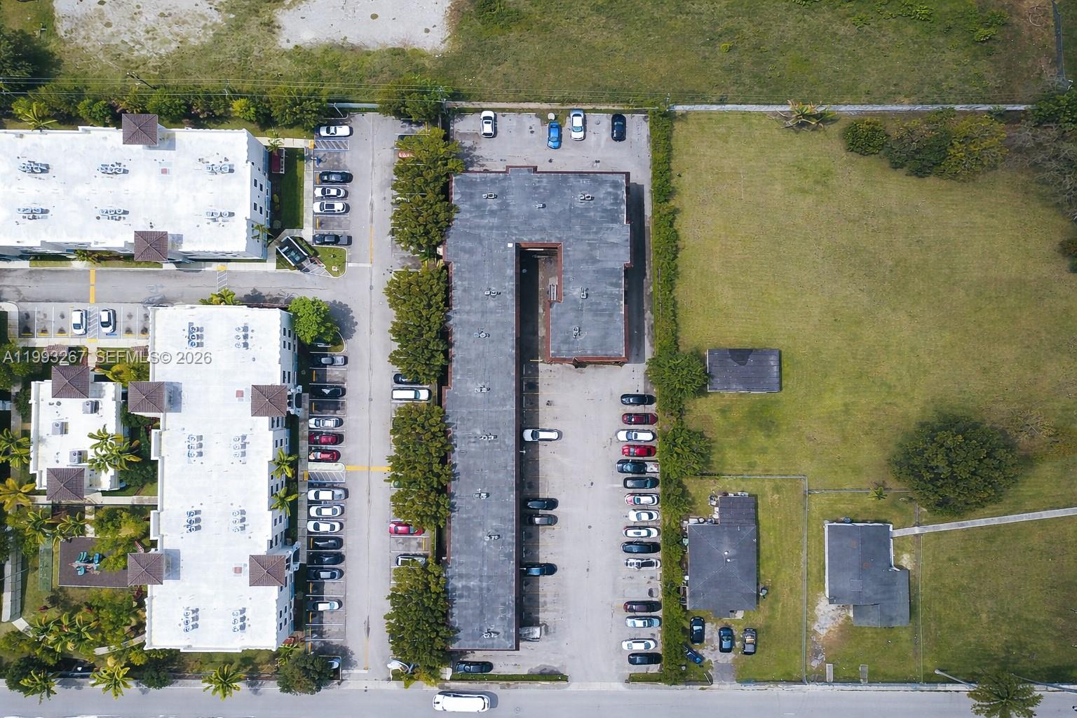 An aerial view shows a multi-story apartment building with a parking lot and adjacent structures — 13380 Port Said Rd, Opa-Locka FL 33054, OPA-LOCKA, FL
