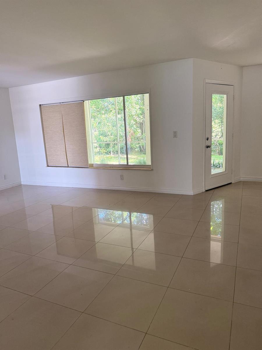 An empty room with large windows, a glass-paneled door, and light-colored tile flooring — 815 West Boynton Beach Boulevard # 103, Boynton Beach FL 33426, BOYNTON BEACH, FL