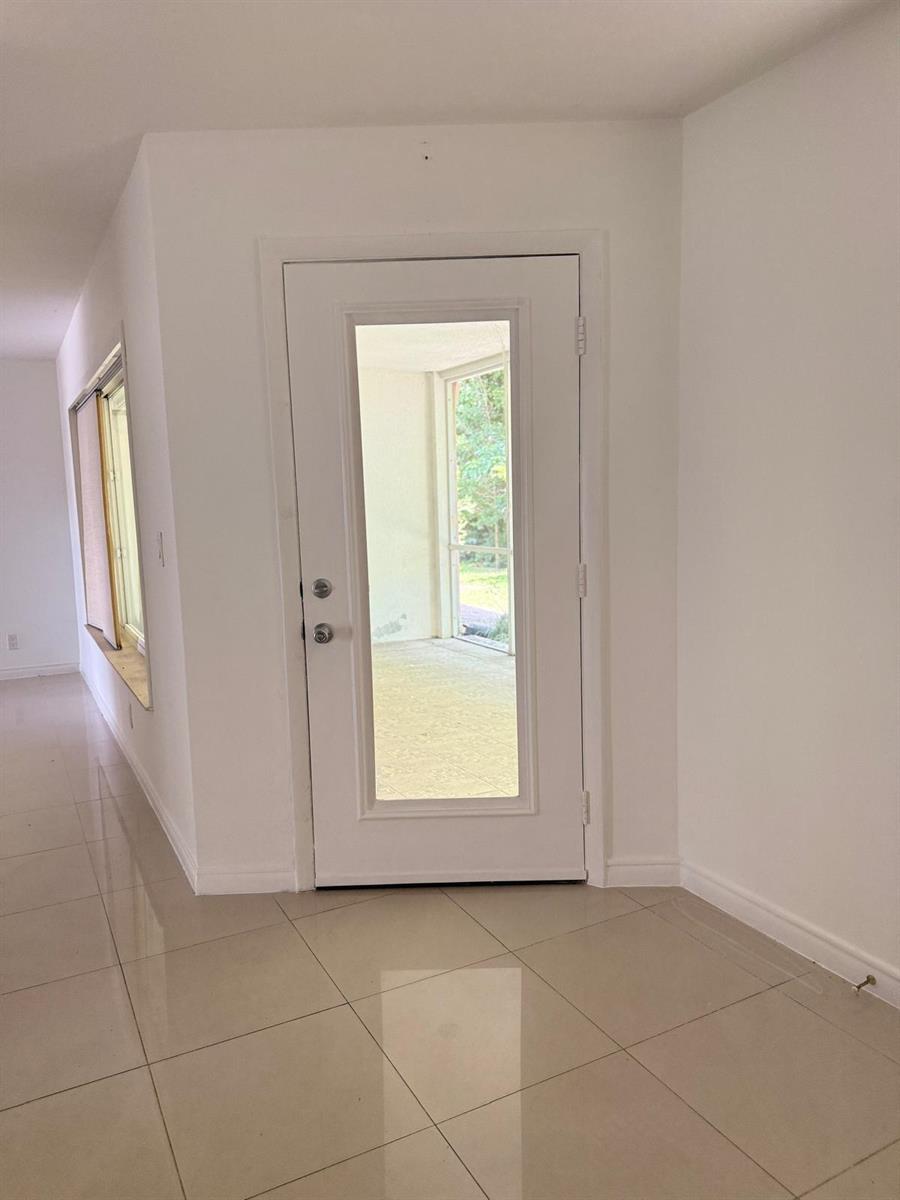 A white door with a glass insert leads to a screened-in porch with tiled floors — 815 West Boynton Beach Boulevard # 103, Boynton Beach FL 33426, BOYNTON BEACH, FL