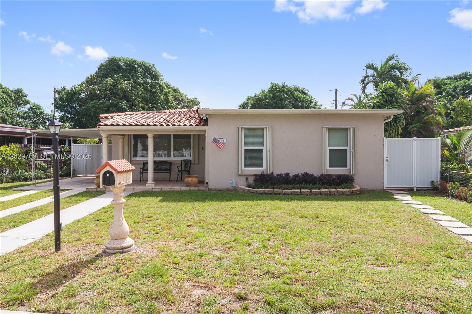 A single-story house with a tiled porch, beige stucco exterior, and a front lawn — 210 E 61st St, Hialeah FL 33013, HIALEAH, FL