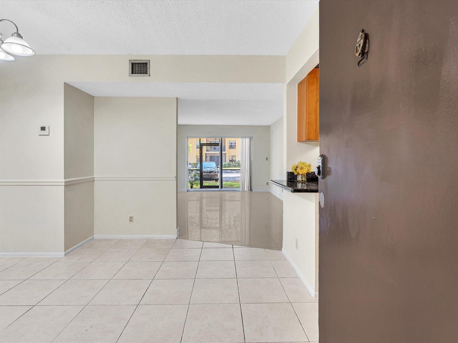 A view from an open doorway into a tiled living area with a sliding glass door — 470 NW 20th Street, Boca Raton FL 33431, BOCA RATON, FL
