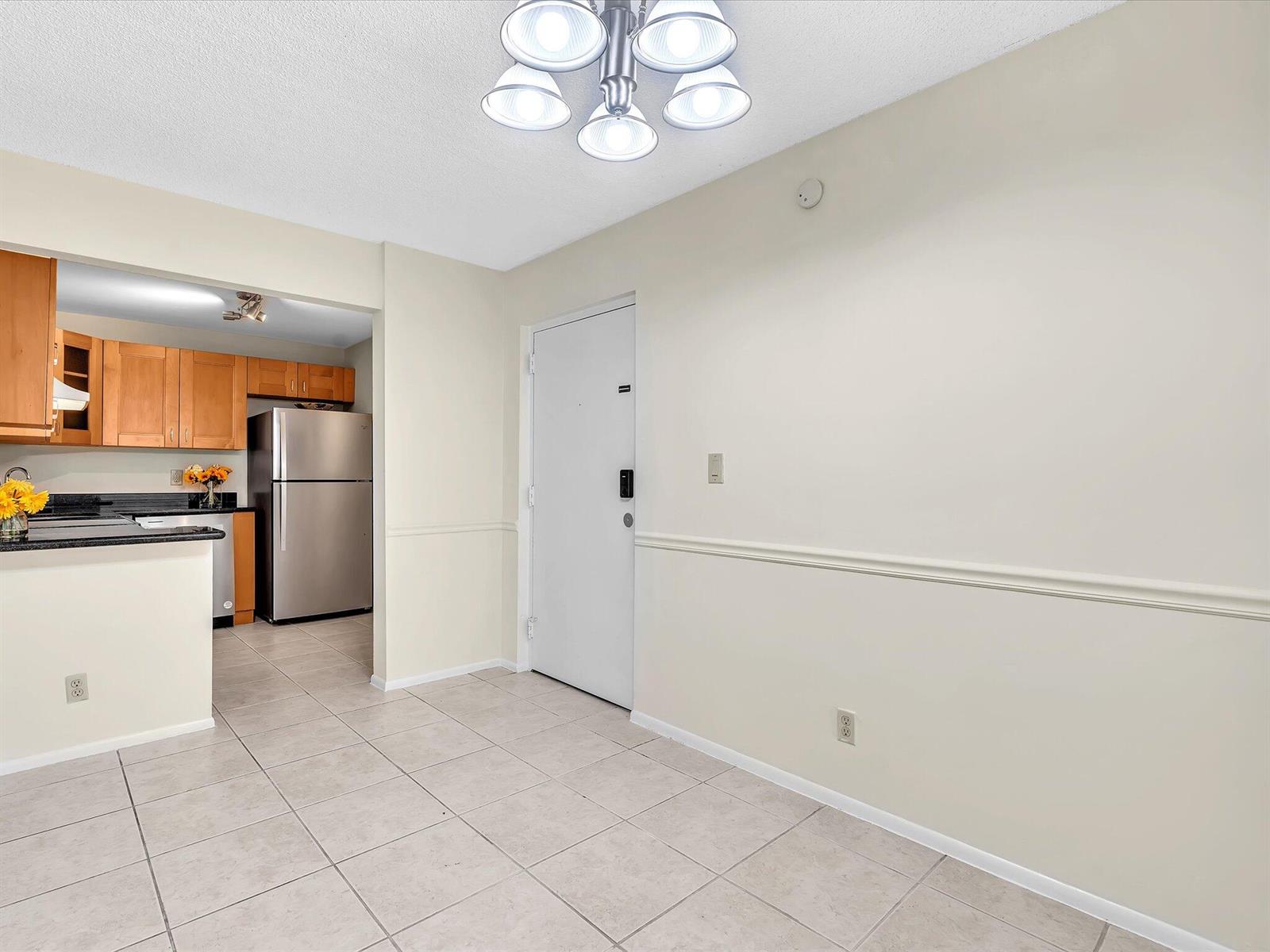 A dining area with tile flooring, a white door, and a view into the kitchen — 470 NW 20th Street, Boca Raton FL 33431, BOCA RATON, FL