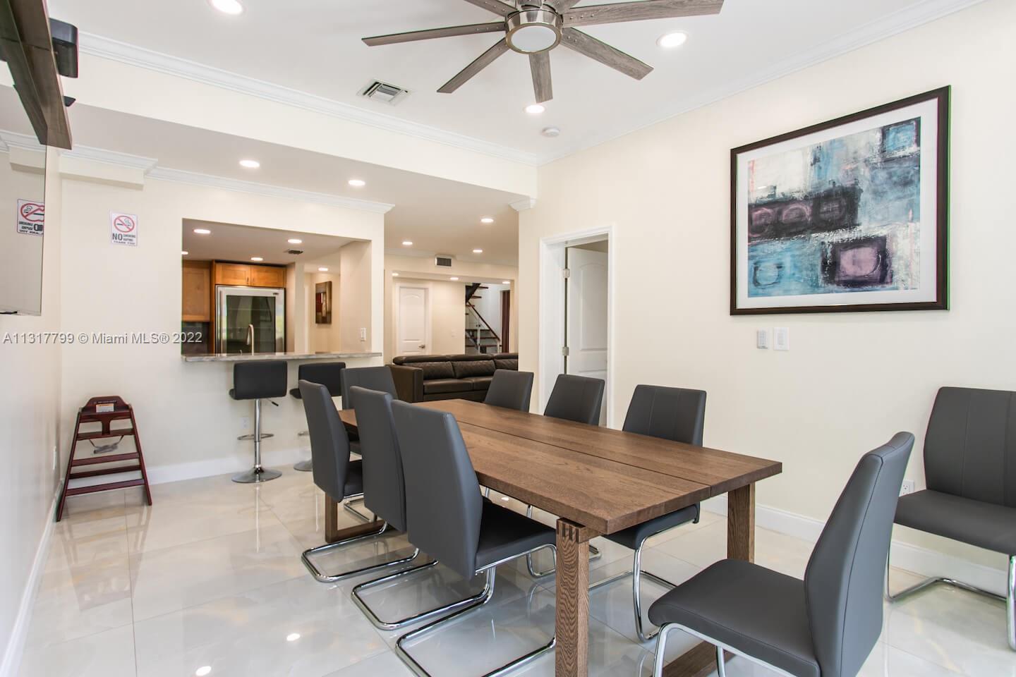 A dining room with a wooden table, gray chairs, and a kitchen pass-through window — 1022 Adams St, Hollywood FL 33019, HOLLYWOOD, FL