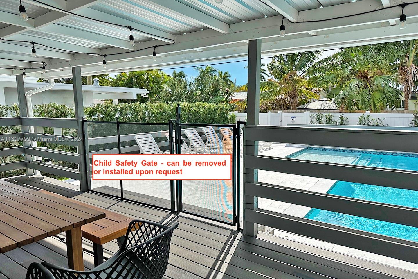 A covered wooden deck overlooks a swimming pool and features a removable child safety gate — 1022 Adams St, Hollywood FL 33019, HOLLYWOOD, FL