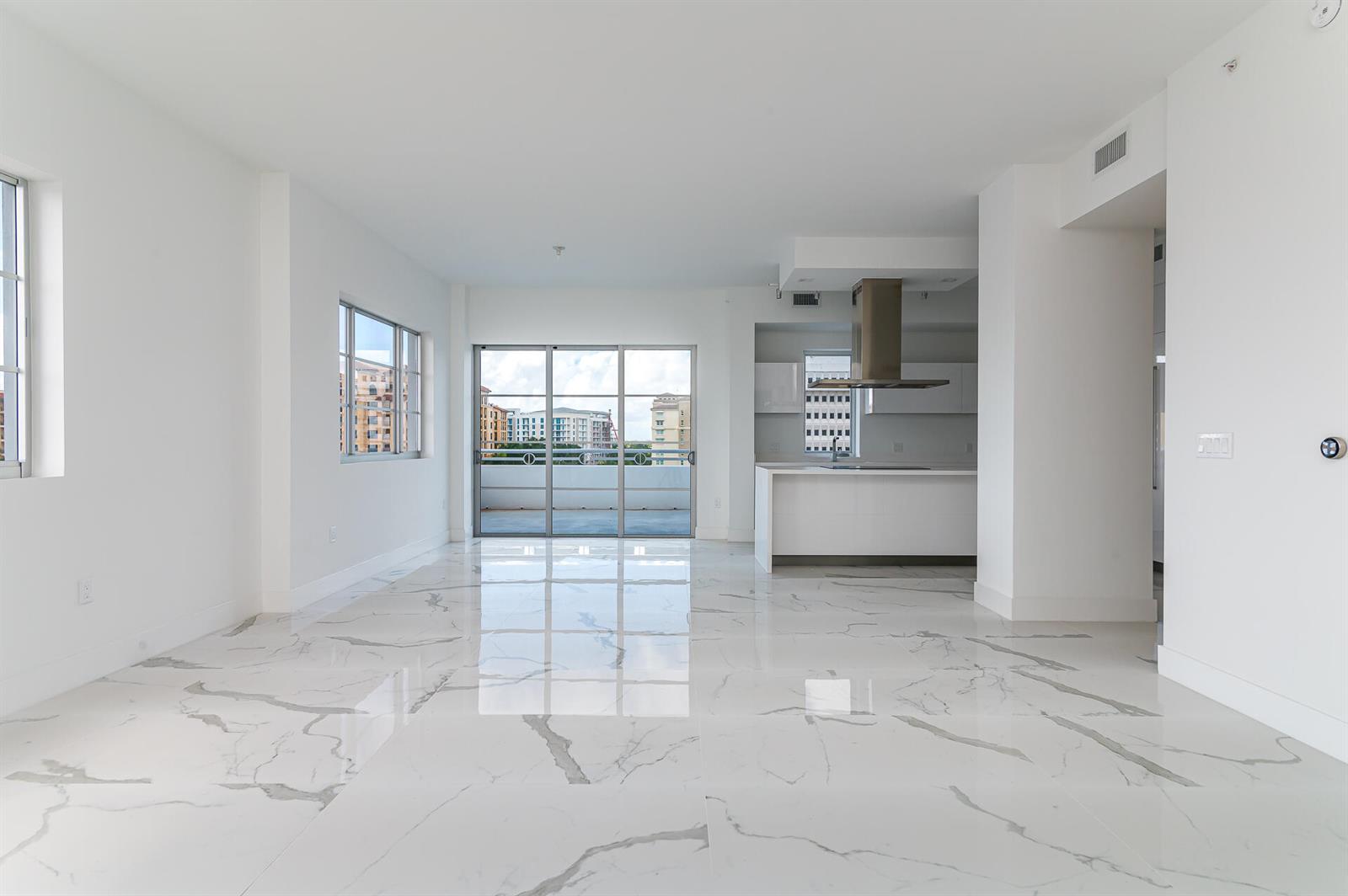 An open-concept living area features white marble-look tile flooring, a modern kitchen, and balcony access — 155 E Boca Raton Road # 603, Boca Raton FL 33432, BOCA RATON, FL