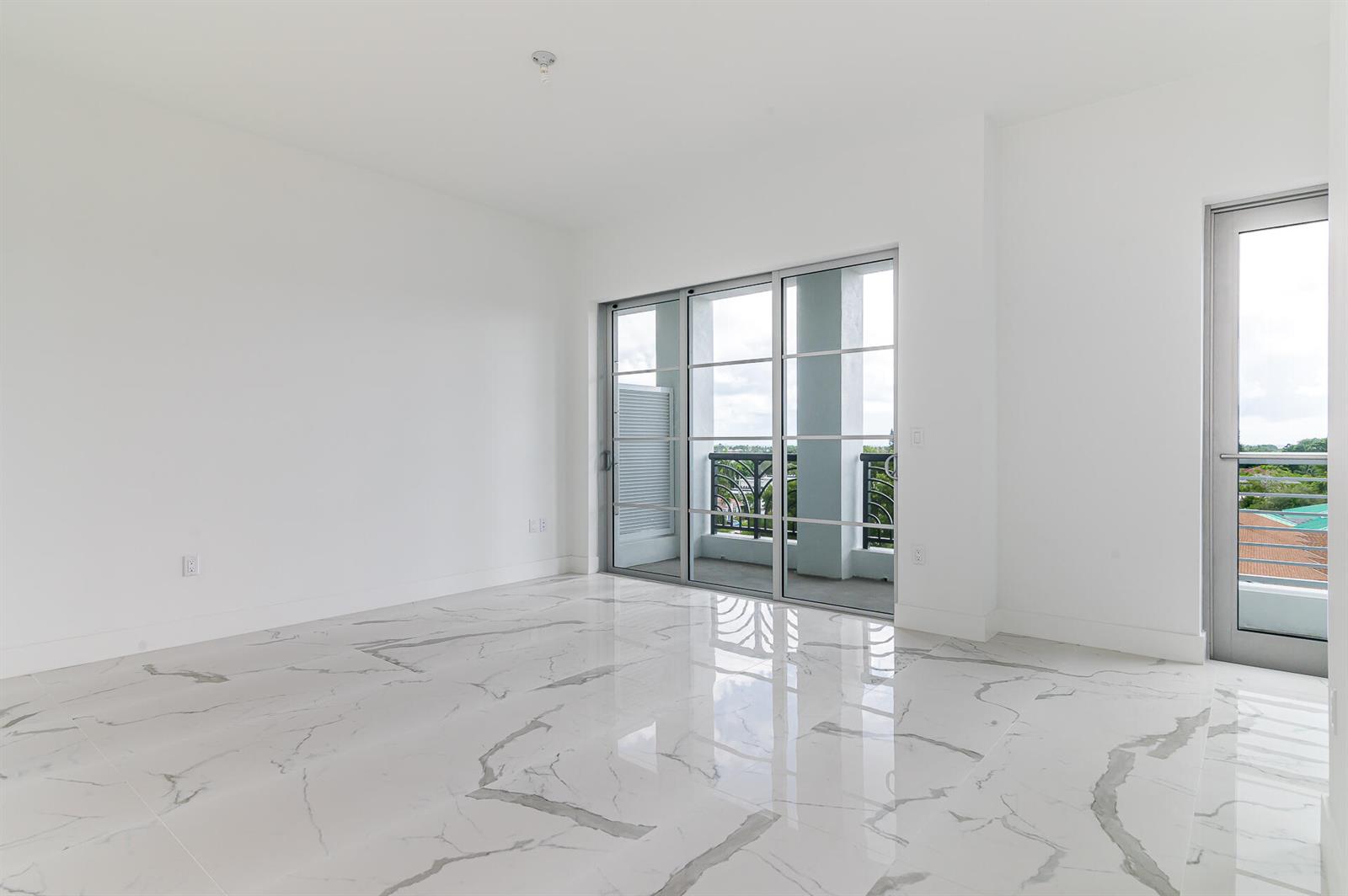 An empty room with white walls, marble-patterned tile flooring, sliding glass doors, and a balcony — 155 E Boca Raton Road # 603, Boca Raton FL 33432, BOCA RATON, FL