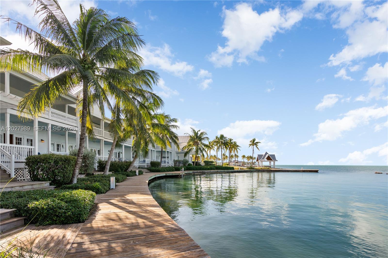A wooden boardwalk curves along the water's edge next to multi-story buildings and palm trees — 2600 Overseas Hwy # 85, Marathon FL 33050, MARATHON, FL