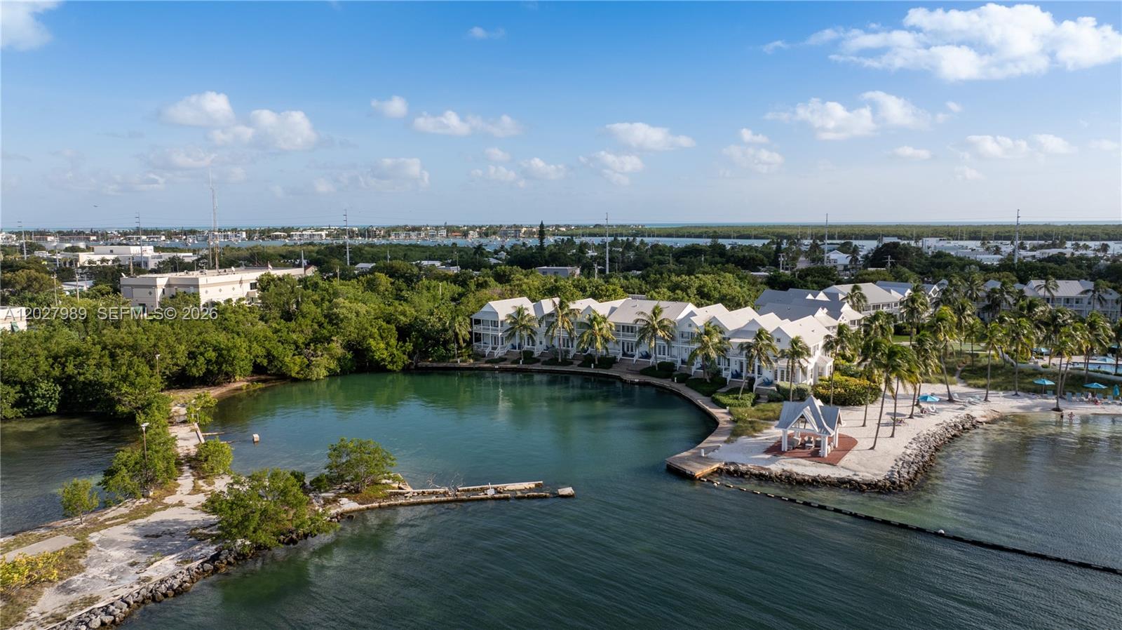 An aerial view shows white townhomes situated along a small, sheltered lagoon with palm trees — 2600 Overseas Hwy # 85, Marathon FL 33050, MARATHON, FL