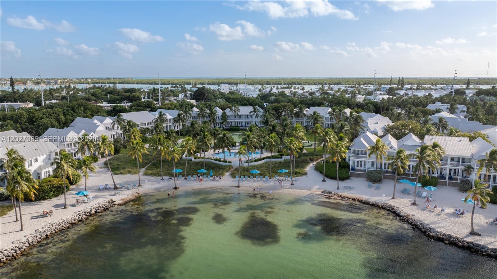 An aerial view shows a beachfront resort with white buildings, palm trees, and a pool — 2600 Overseas Hwy # 85, Marathon FL 33050, MARATHON, FL